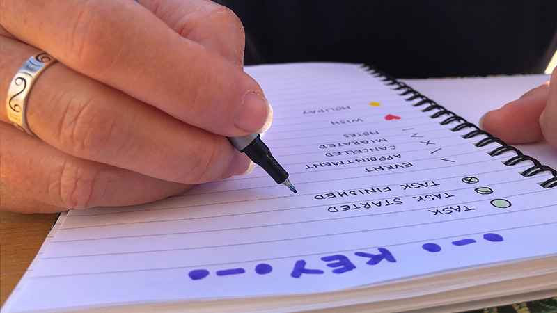 An image of a student writing study goals in a notebook or using a goal-tracking app. The image can show a checklist with study-related tasks or a SMART goals template on a whiteboard or digital screen.